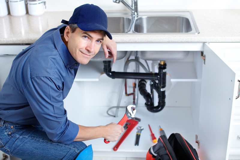 Regular plumber in uniform fixing the kitchen sink